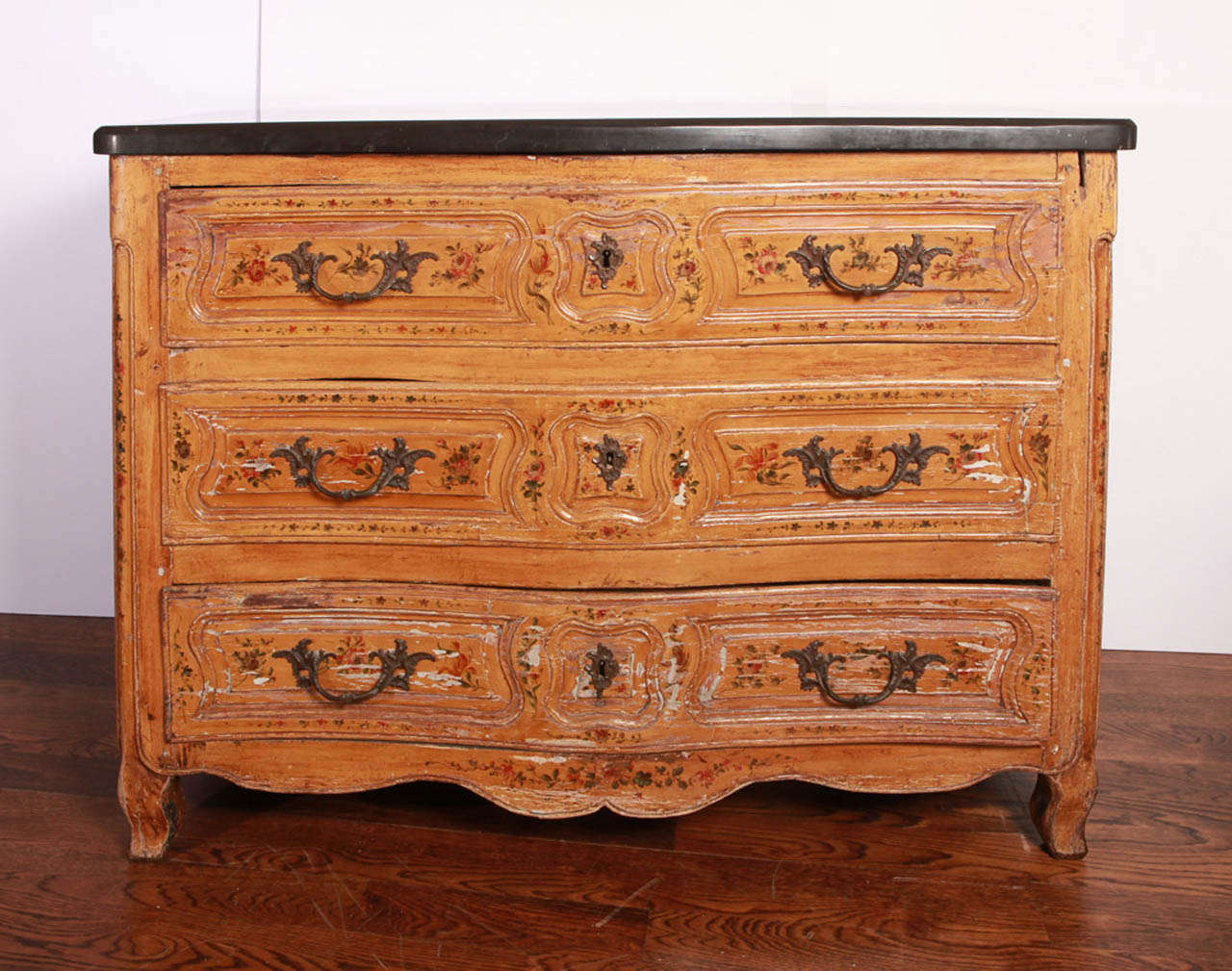 Commode has serpentine front. The three drawers and sides of commode are painted with foliate sprays. Black marble top. Bronze hardware. Cabriole legs.  Previously owned by Consuelo Vanderbilt Balsan.