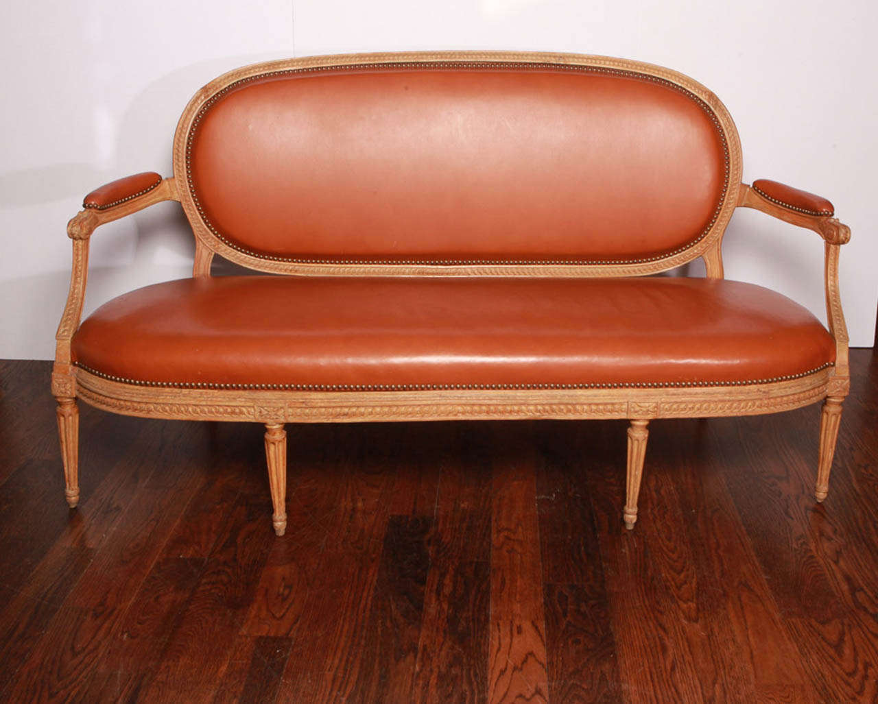 Carved beechwood frame with chestnut leather seat, back and arms. Back and seat are removable. Brass studs. Stamped 