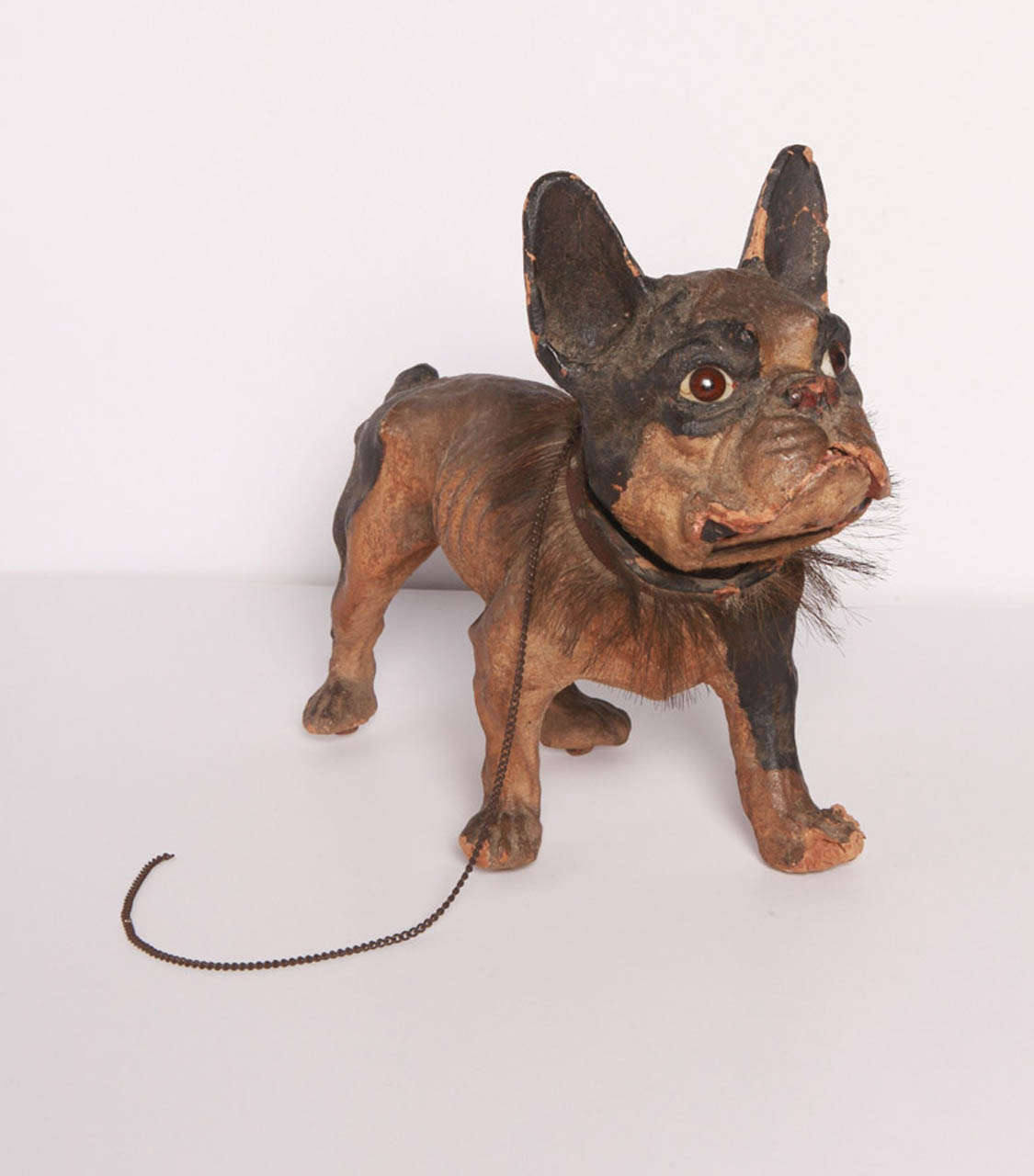 This French bulldog toy was created in homage to the popular late nineteenth century breed.  The papier mache toy is life size in stature, has glass eyes, is set on wood casters and is adorned with a leather collar with hair fringe and chain leash. 