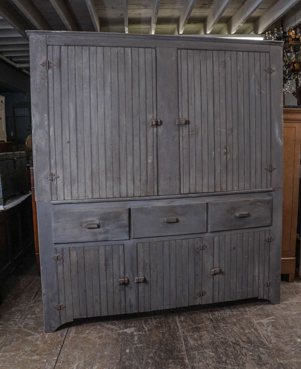 This country kitchen hutch has generous storage space, four shelves above that run the full length behind double paneled doors, three deep drawers in the center and three separate cupboards below. A centerpiece painted gray perfect for a country