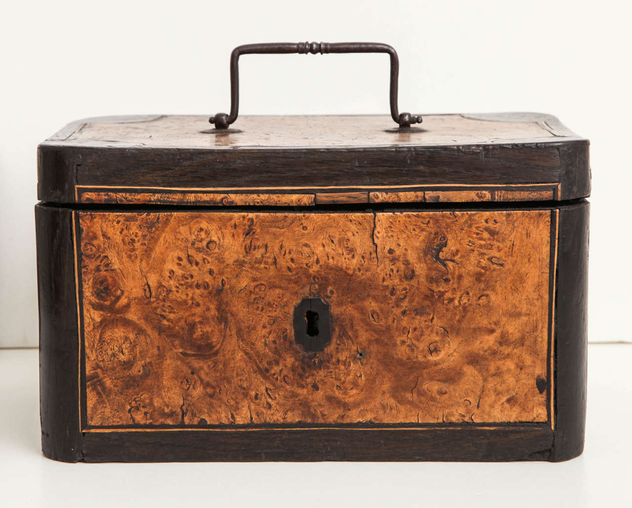 A mid-18th century English bog oak box with richly figured contrasting burr walnut panels and a steel carrying handle, circa 1750.
