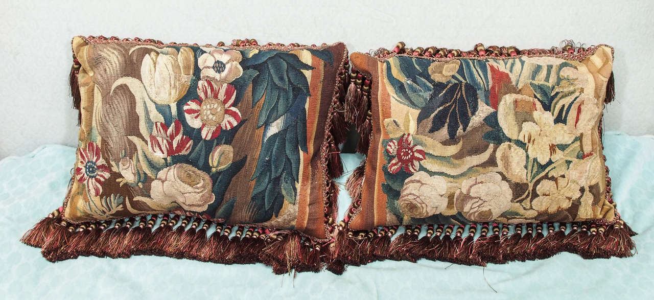 Pair of 17th century Aubusson tapestry fragments now as cushions having silk velvet backing and trim with down inserts.