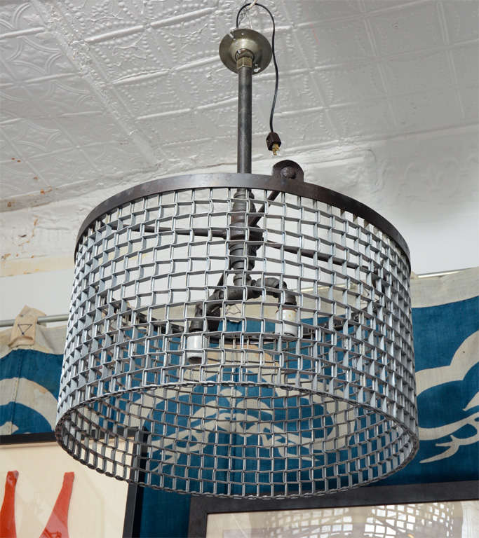 Factory conveyor belt grating fashioned into chandelier. Reclaimed Cast Iron band at top holds 4 antique pipe fittings with ceramic fixtures. UL Rated 200 watts. Available in larger size as well as square. 