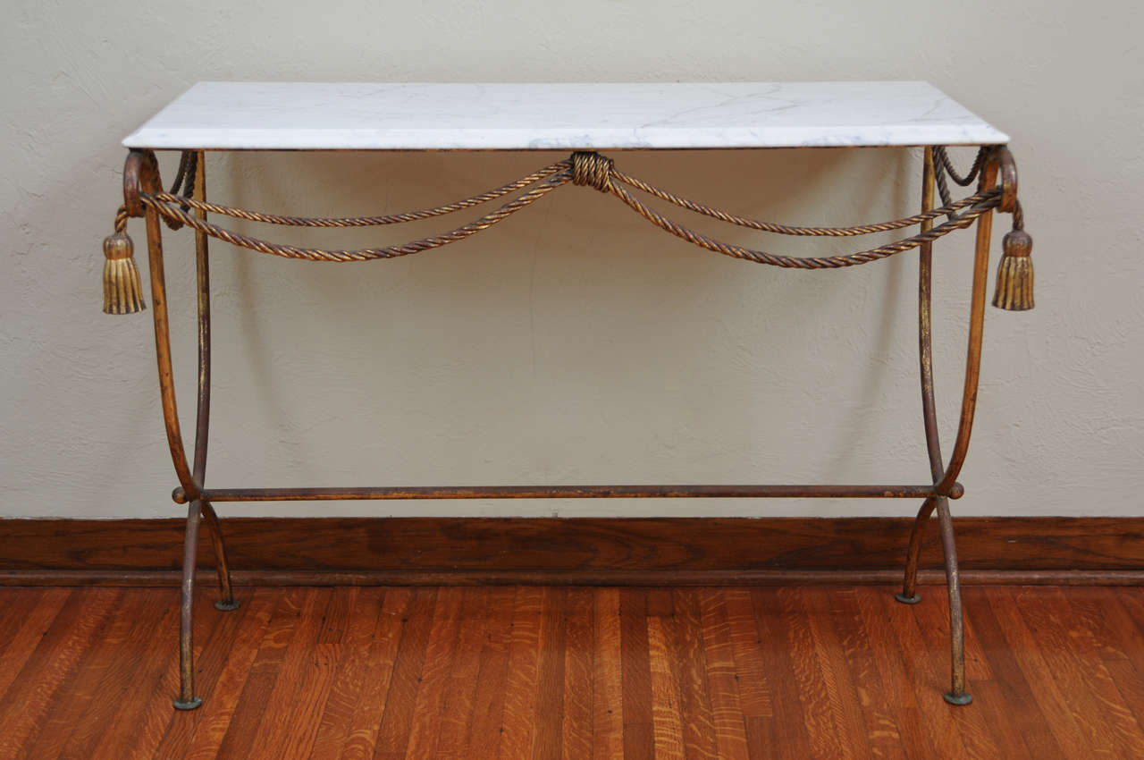 1940's Italian console table.   Carrara marble top on a gold gilt metal base with rope and tassel details.