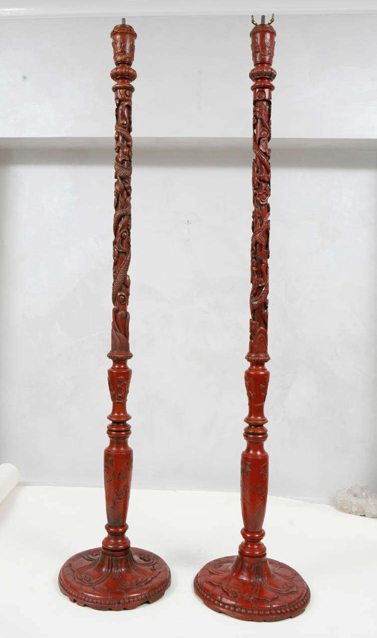 Late 19th century - 1900s pair of Chinese carved wood and painted red pricket sticks that have been converted to floor lamps. Although they are not shown with their shades, the shades are included and are handmade of parchment paper. They are