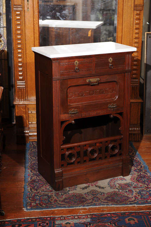 This 1880s Eastlake style cabinet came right out of a barber shop.  Normally there were two of these on separate ends of an area with a long piece of marble connecting them and a giant mirror hanging over them.  The flop-down door is where the