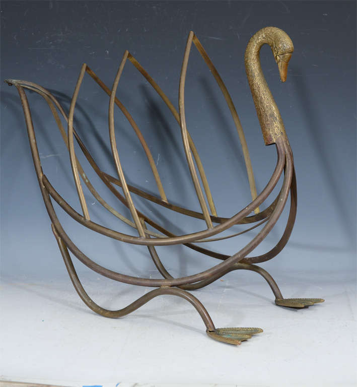 A vintage patinated bronze magazine rack in the shape of a stylized swan. The bird's 