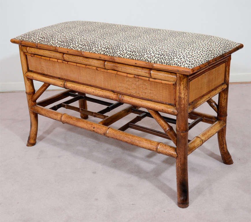 An antique bench with a bamboo frame and recently reupholstered leopard print cushion. The seat lifts up to reveal a storage cabinet.