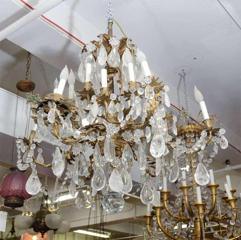 A large, elaborate bronze chandelier with vegetal detailing adorned with clear rock crystals.