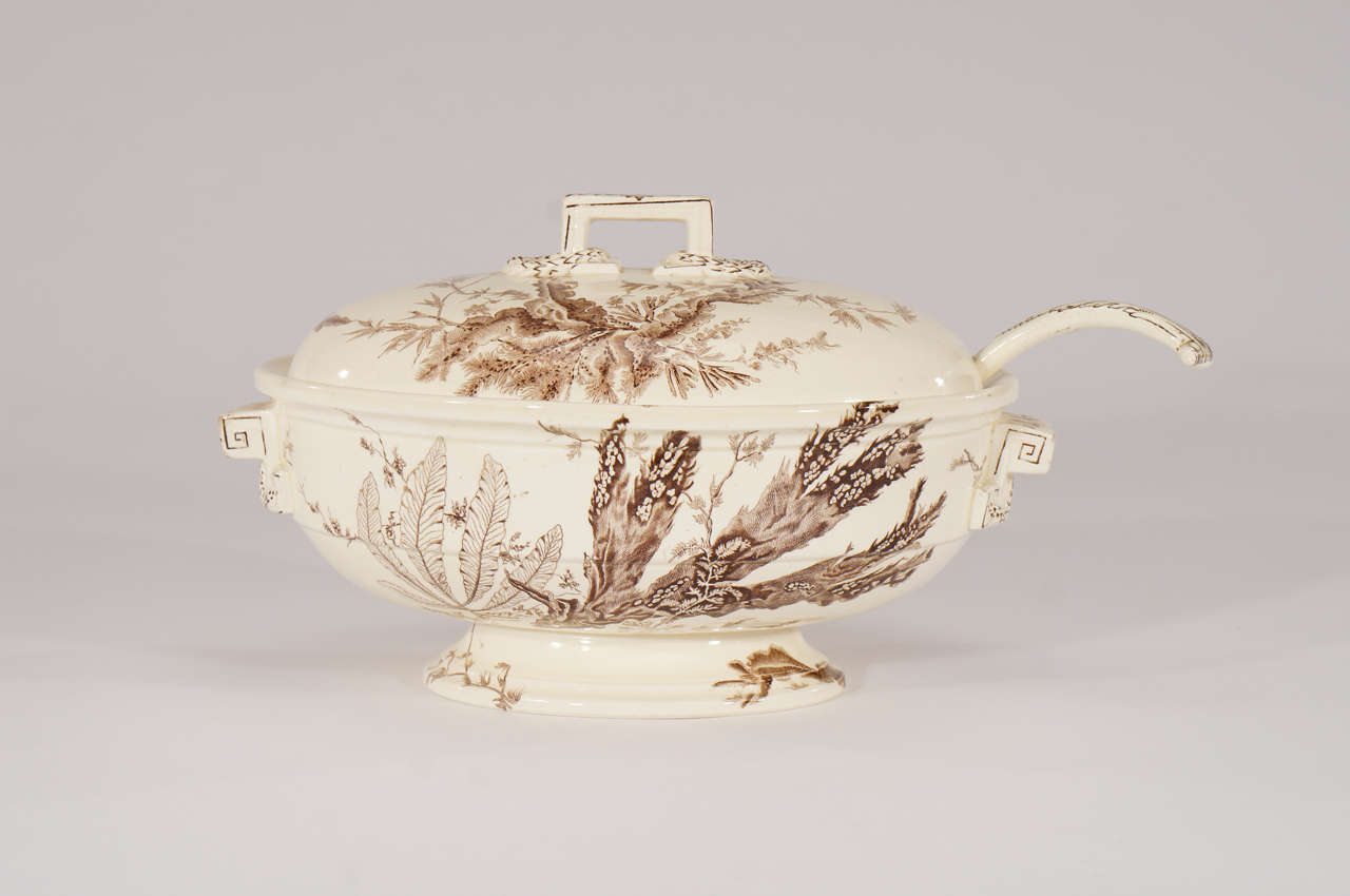 This charming Aesthetic Movement Wedgwood Creamware footed soup tureen is decorated in a brown and white transfer pattern depicting varieties of seaweed. Decorated all around the circumference, it is embellished with a laurel leaf finial and handles