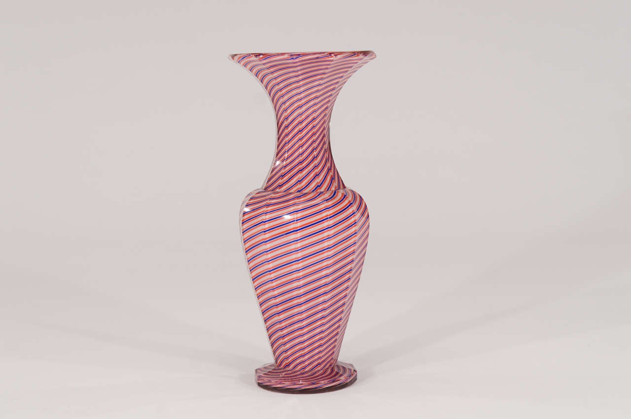 Ce grand vase Saint Louis, bien proportionné, présente tous les attributs de la maîtrise de la verrerie. Il commence par un intérieur blanc, puis est habillé d'une couche de latticino tricolore, avant d'être à nouveau habillé de cristal clair. Il