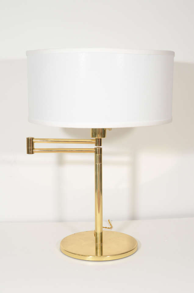 Pair of brass swing-arm table lamps with round base by Hansen.  Spain, circa 1960.  Signed with label.  Recently rewired for U.S. with new French gold silk twist wire and new sockets; each lamp takes one standard bulb.

Dimensions:
21.5