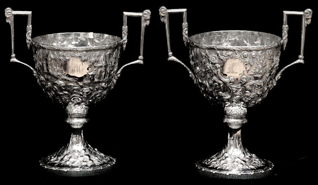 These cups were made by Samuel Kirk who is know for his fine quality intricate silver patterns. The repousse and engraved<br />
flowers, butterflies, buildings and scrolls are a tour de force. There is a reserve on two sides, one with initials and