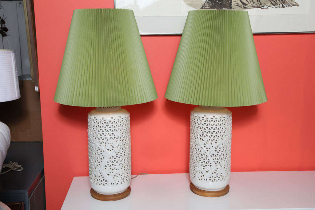 Pair of beautiful ceramic japanese lamps. Depictions of Cherry Blossom trees which hold a special significance in japanese culture are present on the trianglular mesh pattern that comprise the lamps. The green lampshades finish them off with a touch