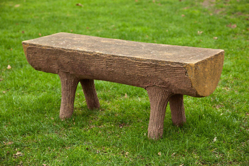 A cast stone faux bois bench with textured bark-like surface on legs and sides.