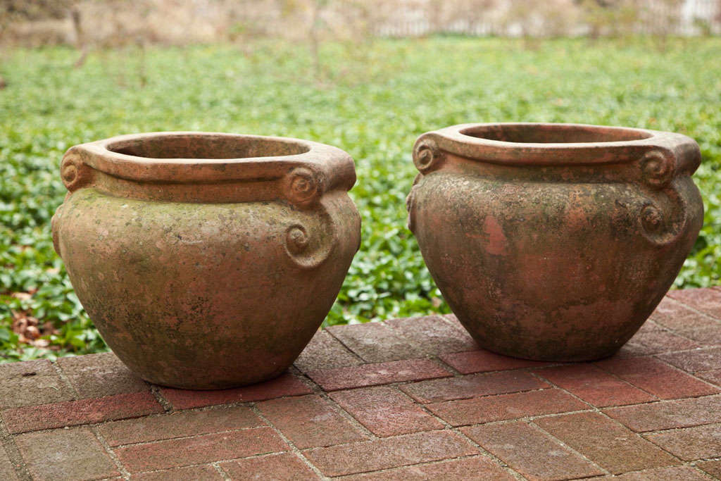 A pair of Compton-style terra-cotta pots of typical rounded form with scrolled handles.