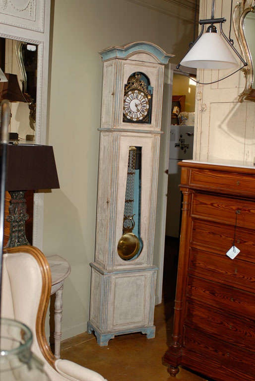 A French Louis XVI style late 19th century painted wood tall case clock with original gilded and enameled face, pendulum and bell. This French grandfather clock features an off-white body painted with light blue accents. The rectangular head, topped