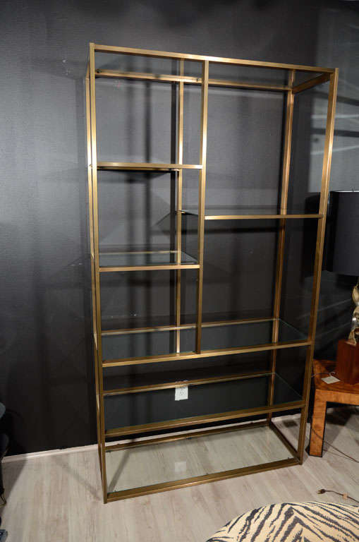Mid Century etagere with multiple<br />
tiers and modernist design. The <br />
shelf unit has a patined brass frame<br />
with glass shelves in varying lengths<br />
and heights, allowing for all types<br />
of books and displays.