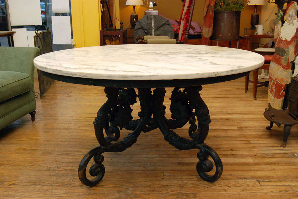 Circular table with dry marble surface and Finely cast iron base. Base comprised of Renaissance revival scrolling building elements radiating from center welds.  beautifully ornate and proportioned.