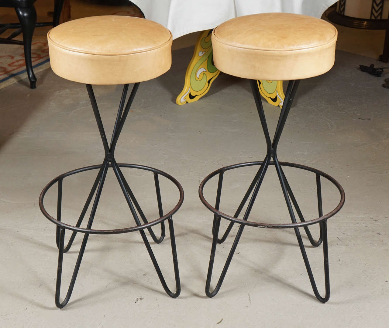 Pair of wrought iron bar stools in the style of Weinberg. Generous foot ring and new leather swiveling seats.