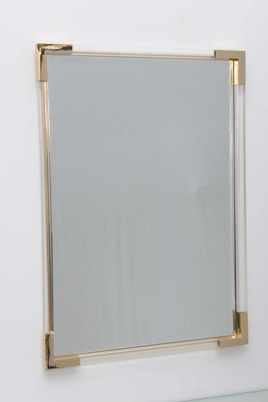 Single mirror featuring a frame made of Lucite with brass corners.