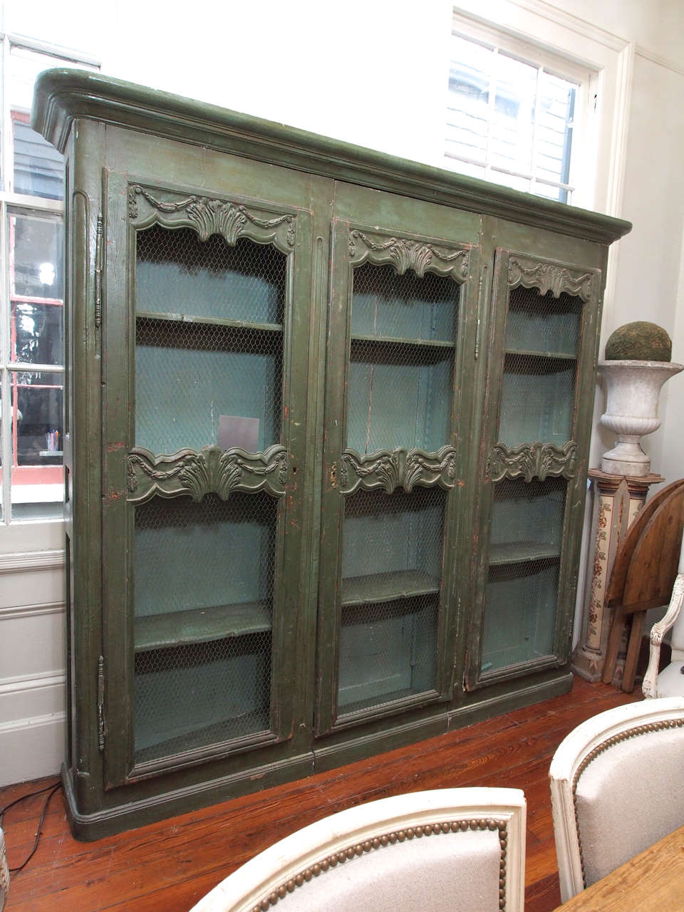 Early 19th century painted bookcase in green (original paint) with three chicken wire doors and three shelves inside.