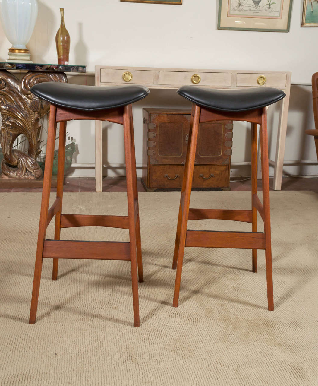 A circa 1950s pair of Teak Danish modern bar stools, with Black leather seats. Designed by Johannes Andersen. Seats have new foam and leather.
