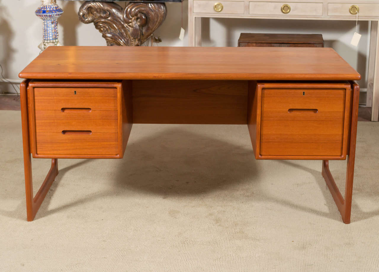 Floating top Teak executive desk, by Dyrlund. Desk has a bookcase front, top is solid plank Teak, right file drawer locks, left side has three drawers, top one locks. All drawers have a wonderful looking carved Teak handles.