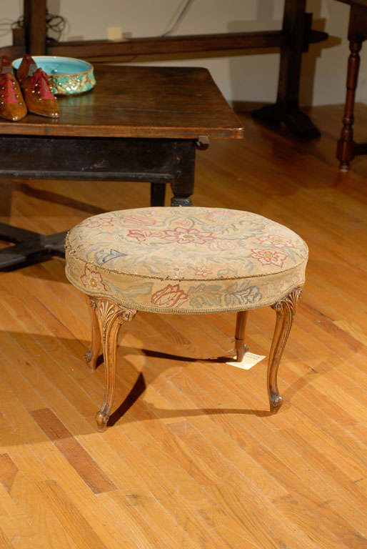 This wonderful needlepoint stool is standing on four cabriole carved legs.  The needlepoint has a handsome floral design on top and it continues on the sides.  The top portion of the needlepoint is separated by cording.  The needlepoint is original