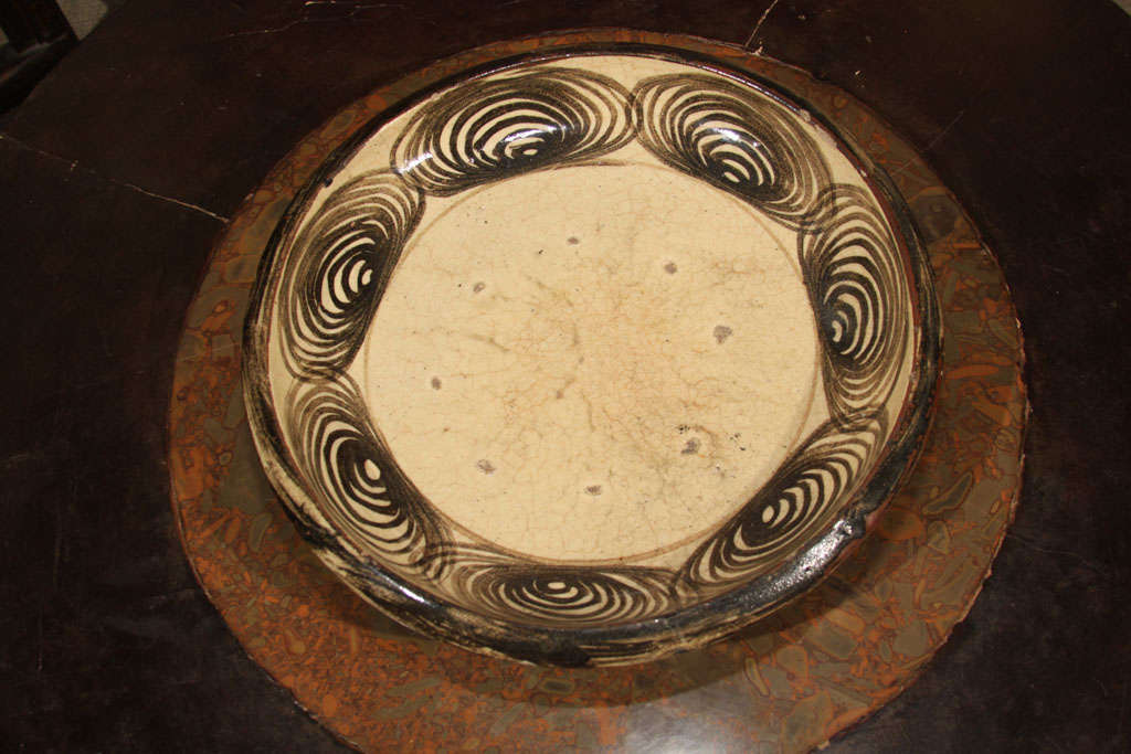 Japanese Seto ware horse eye plate ({uma no me zara}) with iron oxide painted decoration. The border decorated with seven freely painted ovals (horse eyes) of concentric circles. The plate with cream color glaze covered with a fine network of