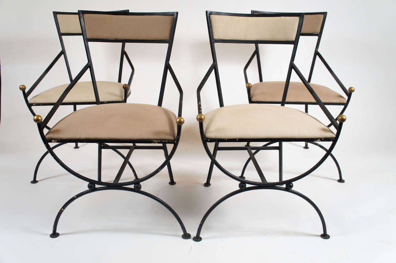Elegant set of four c. 1950 wrought iron and bronze curule form garden chairs having upholstered seats and backs.