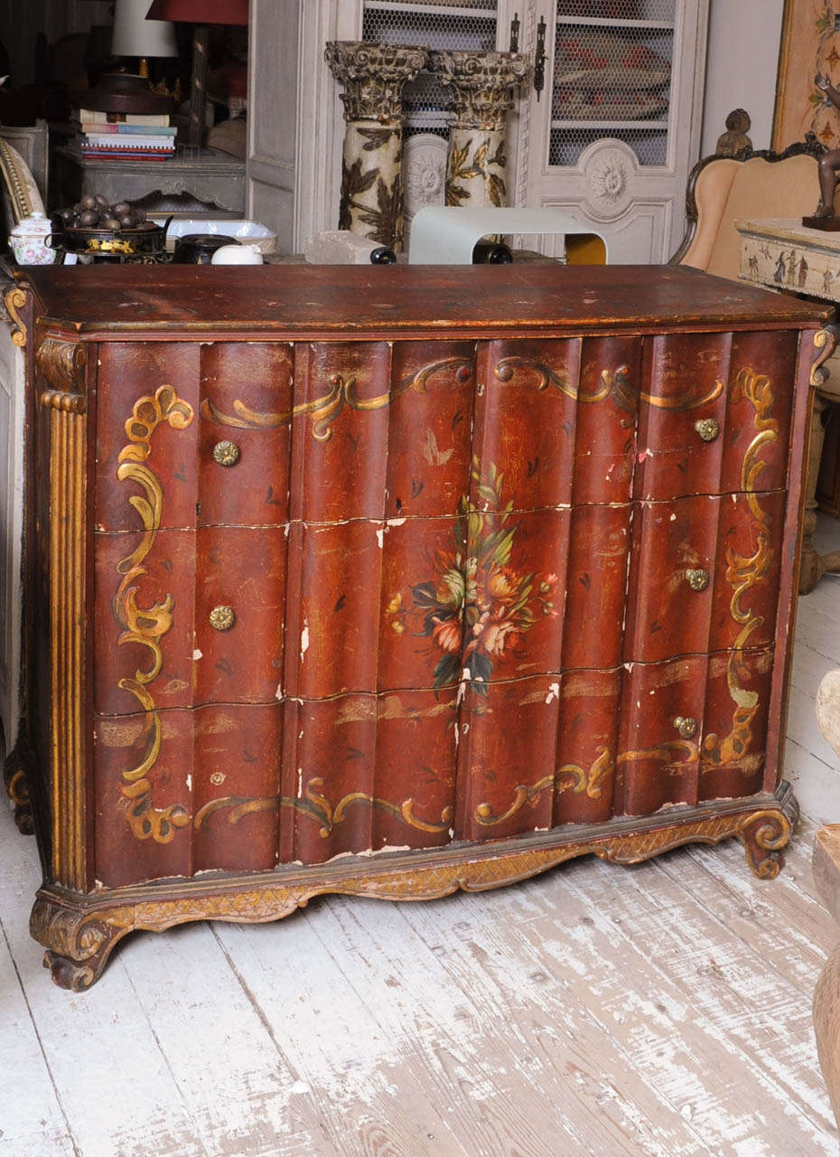 Italian organ bowed chest of drawers, painted in red with flowers and goldened decorations