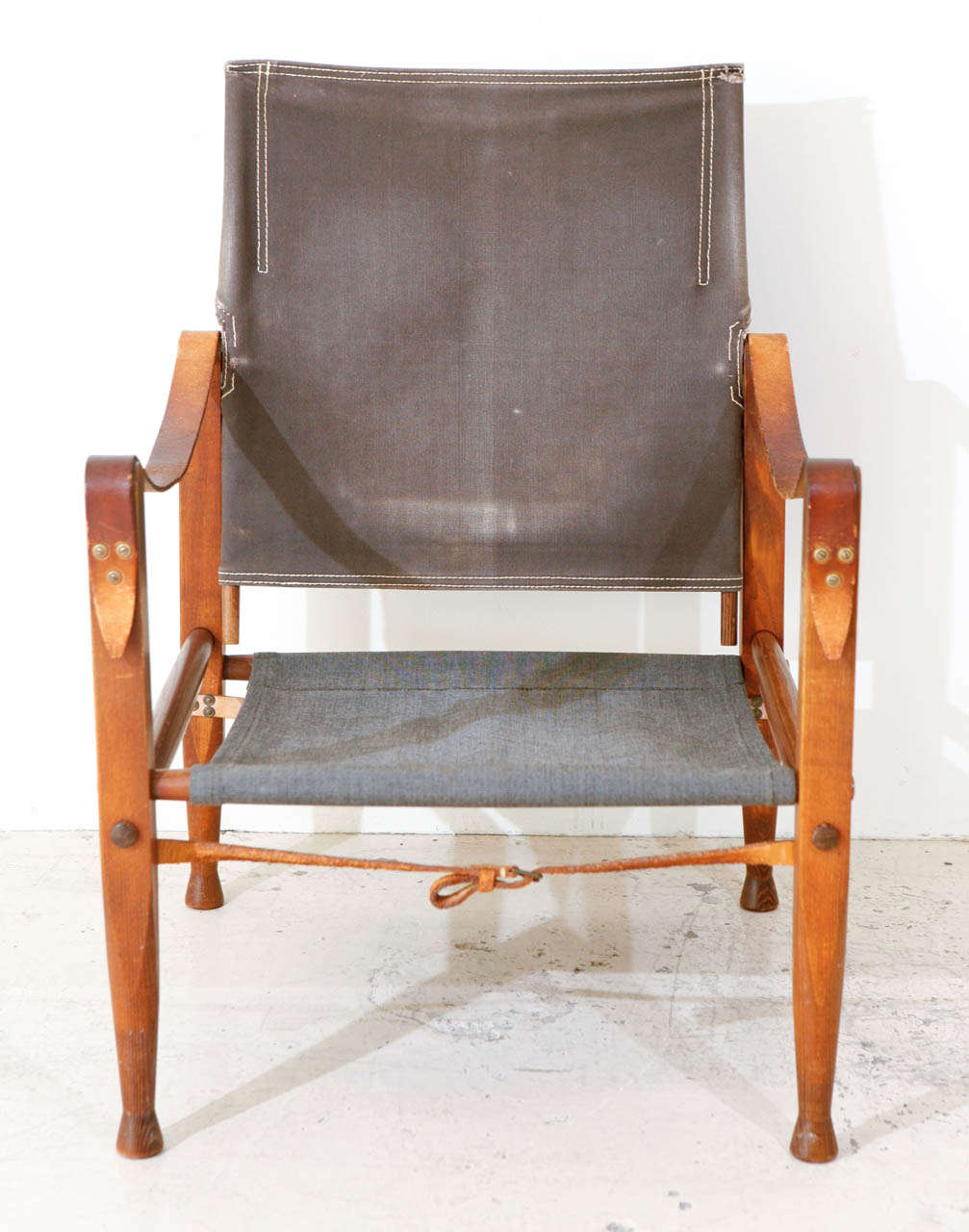 Safari chair by Kaare Klint. Made by Rud Rassman Denmark. Dark ash frames with original canvas seat and pivoting back and original leather arm straps.