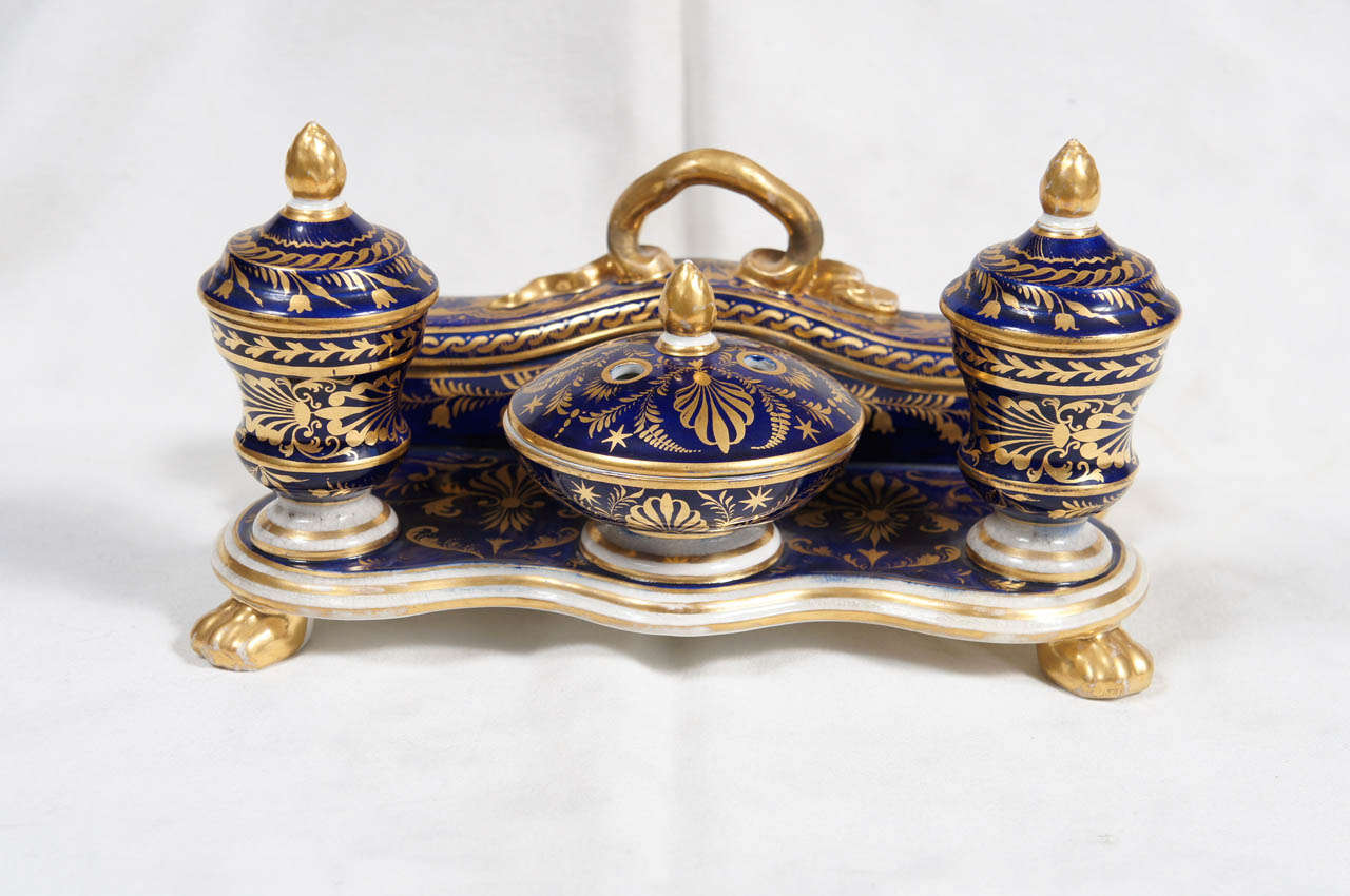 Royal Crown Derby Porcelain Inkwell, footed inkstand with three pots and covered pen tray decorated in dark blue and gilt.
