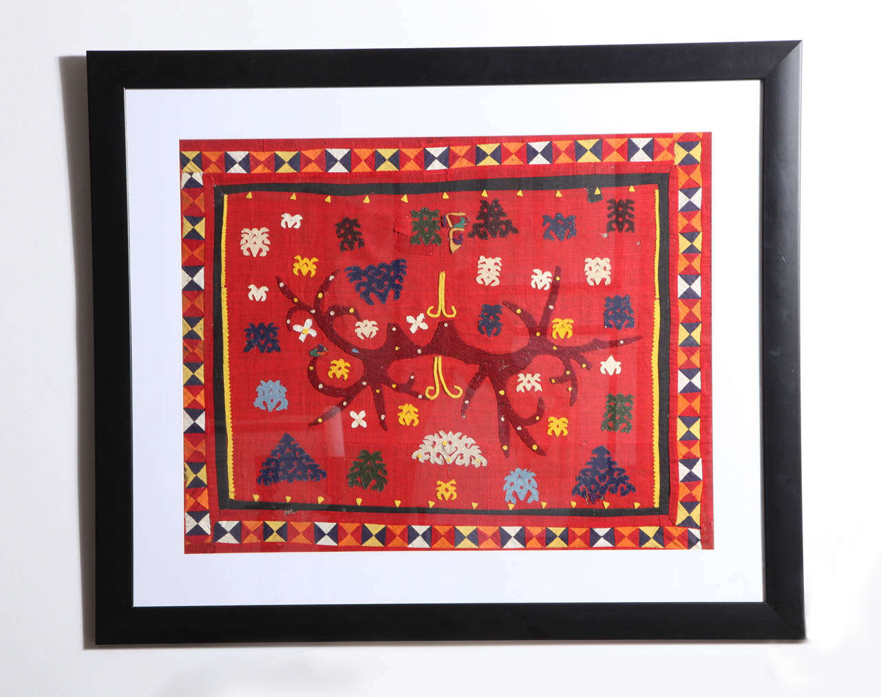 A framed Lampung Fabric from Sumatra. Hand-stitched appliques on red cloth in a traditional design.  100 years old.