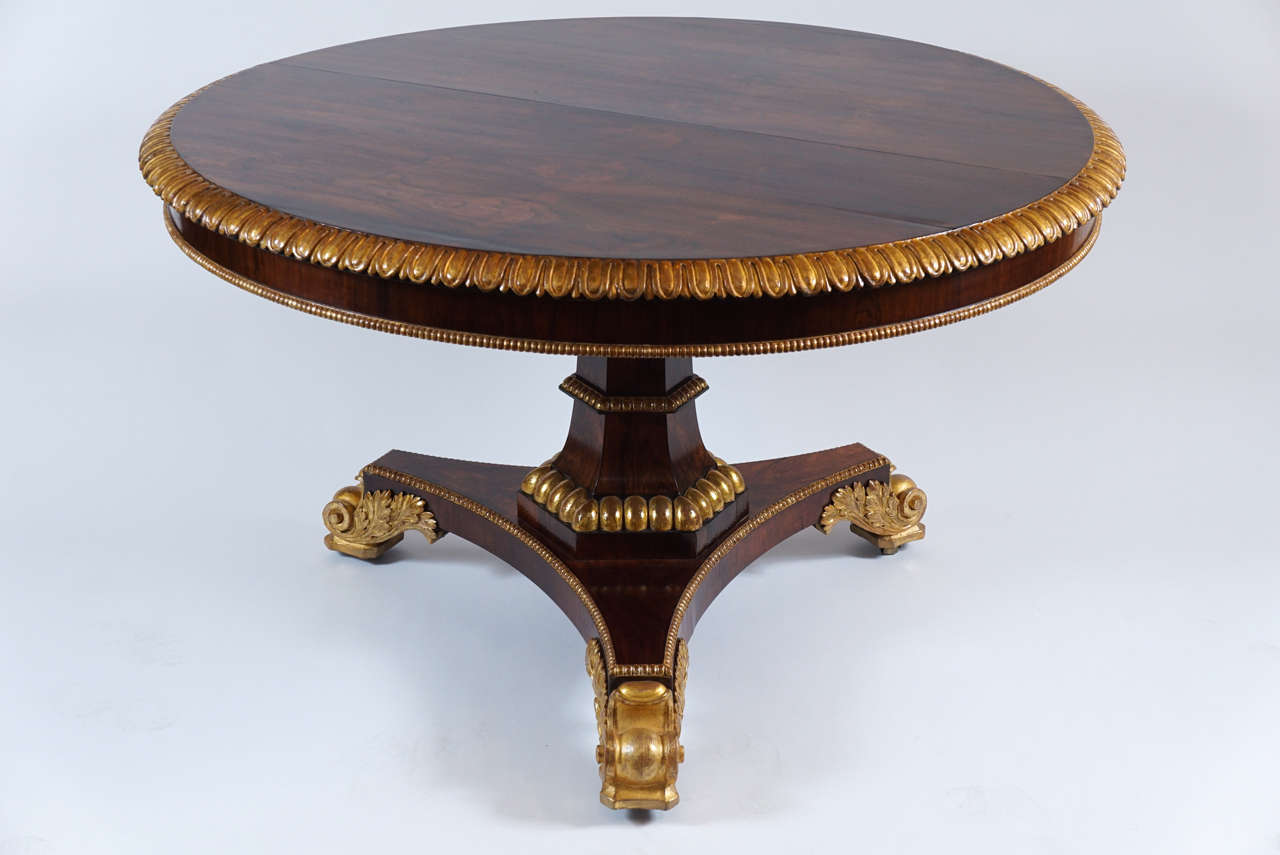 An extremely fine English George IV regency style parcel-gilt rosewood center table attributed to Gillows of Lancaster after exact designs published by the firm in 1823. The large circular tilt-top with exquisite bookmatched veneers having a 'lambs