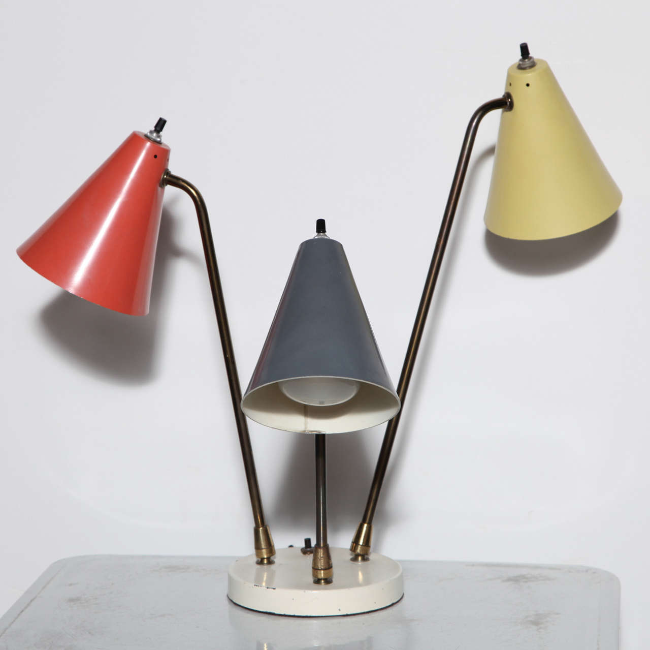 Mid Century Gino Sarfatti style adjustable Desk Lamp. Featuring: 3 enamel Shades in 3 colors: 1) Shade in Tomato Red, 2)  Shade Medium Gray 3) Shade Cream Yellow, 3 articulating Brass arms. Arms adjusts at Base and Head with each arm at different