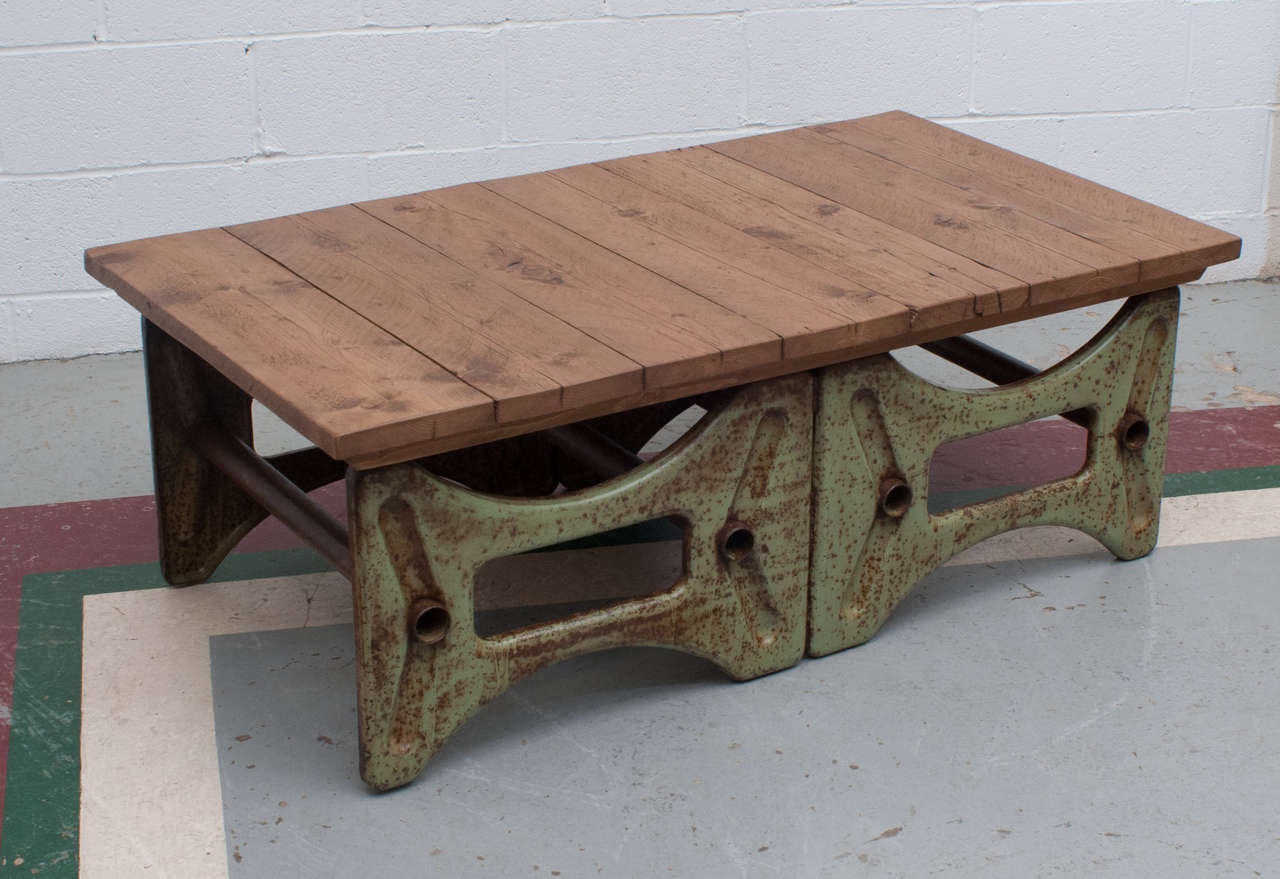 A rugged coffee table on a cast iron Industrial base in rusted original green paint with a polished top from reclaimed pine.