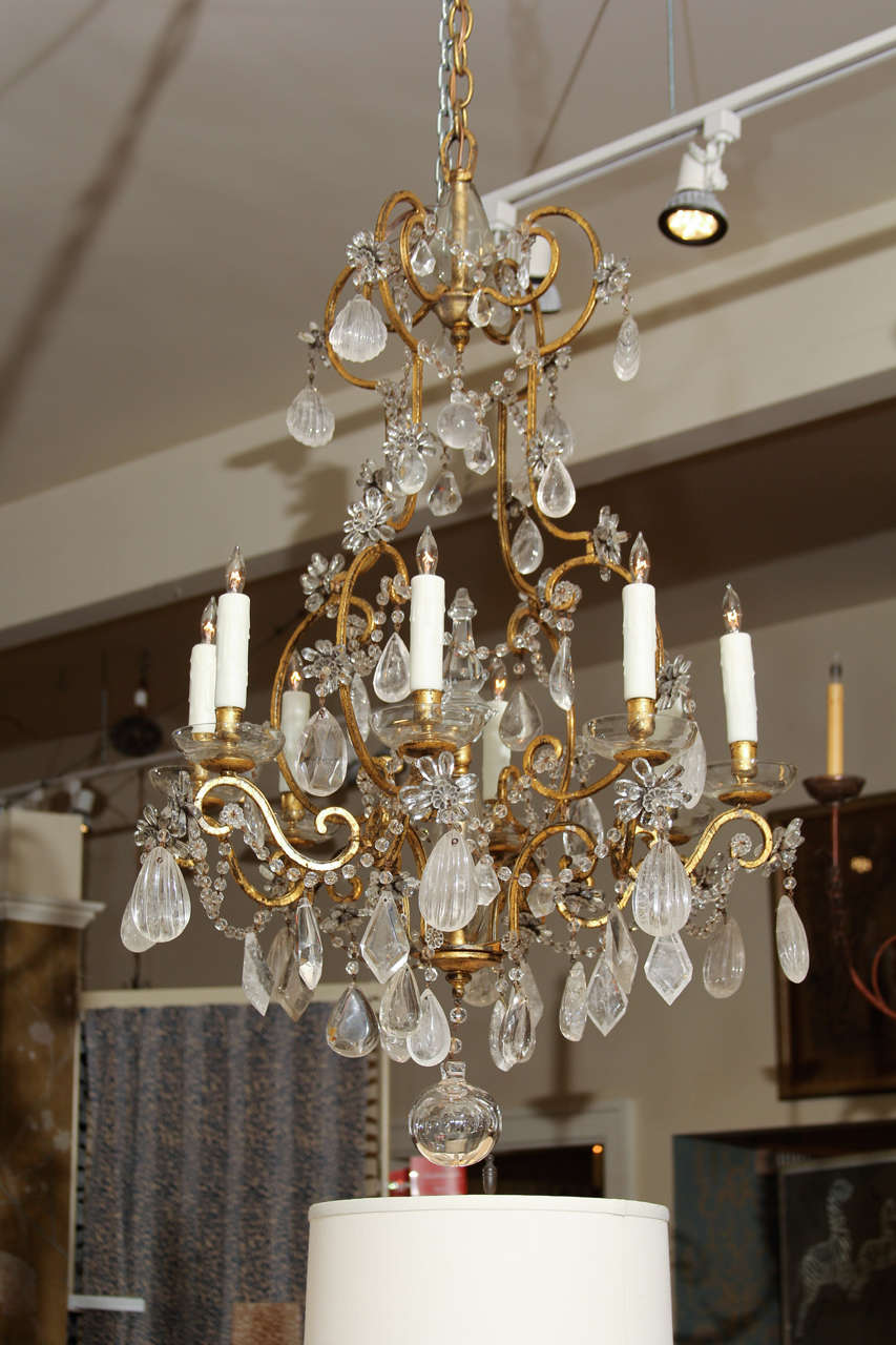 A French mid-20th century wrought iron cage chandelier with an antique gold finish and dressed with rock crystal and glass beads. Recently re-wired and fitted with polymer candle covers.