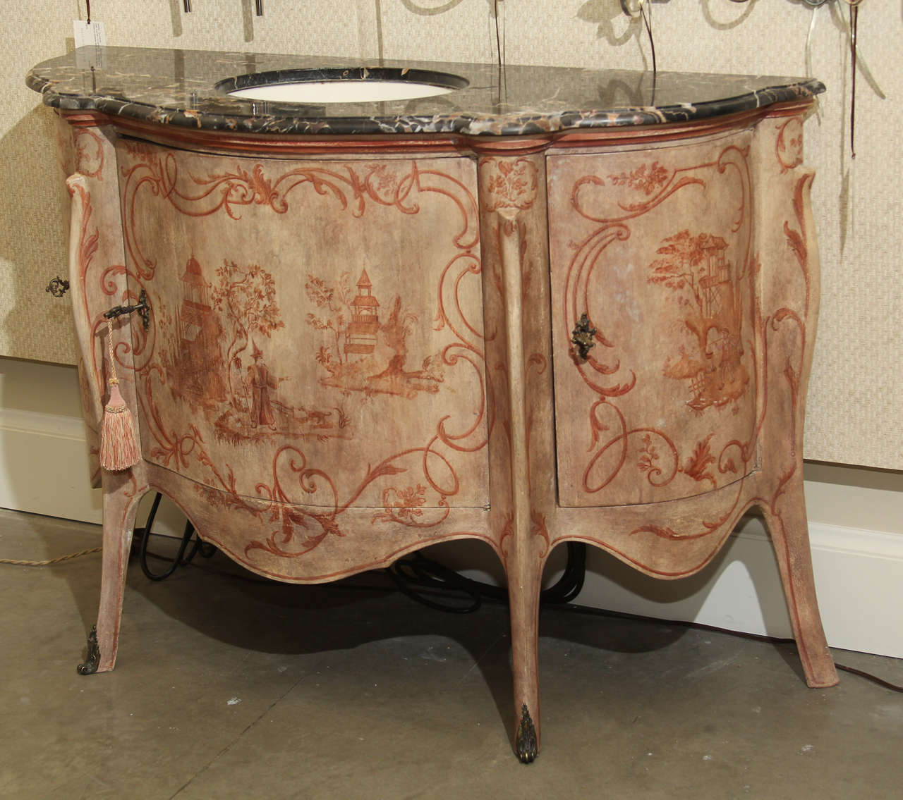 A high quality hand-painted reproduction of an 18th century Italian commode decorated with chinoiserie figures. The marble top has an inset porcelain sink. The spigots would have originally been on the wall. Two side doors open for storage.