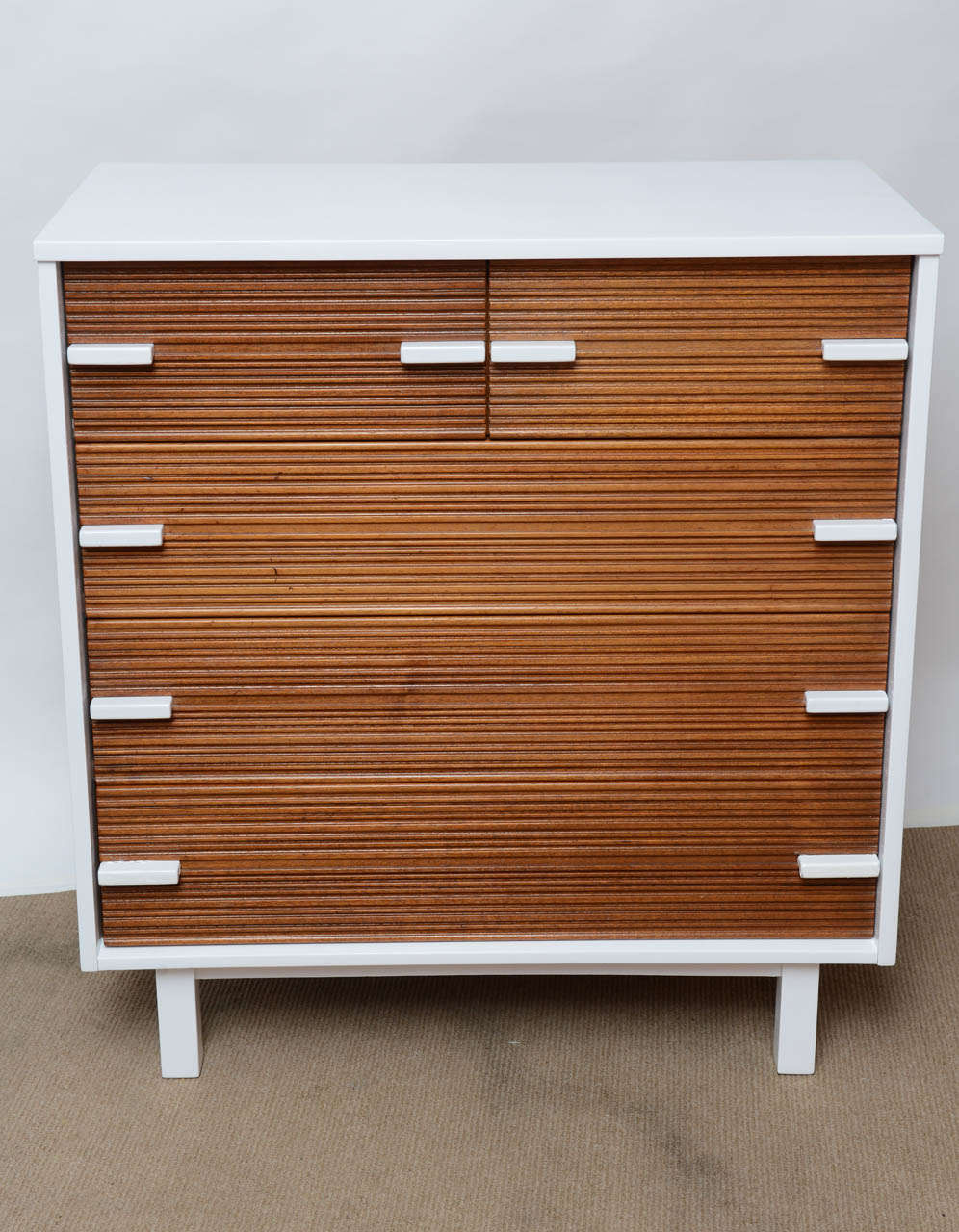 This mid-century modern tall Chester has been beautifully refinished by our Furniture Restoration Division. The body and the handles lacquered in white Polyurethane High gloss bring the sculpted drawers more stunning. Elegant and compact, this piece