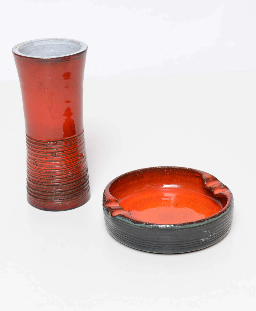 Take your living room back to the latest Mad Men set with these perfect accessories.  Set includes a handmade ceramic cylindrical vase in orange red and black.  Round out the retro look with a  matching hand-finished ashtray in the same color. Vase