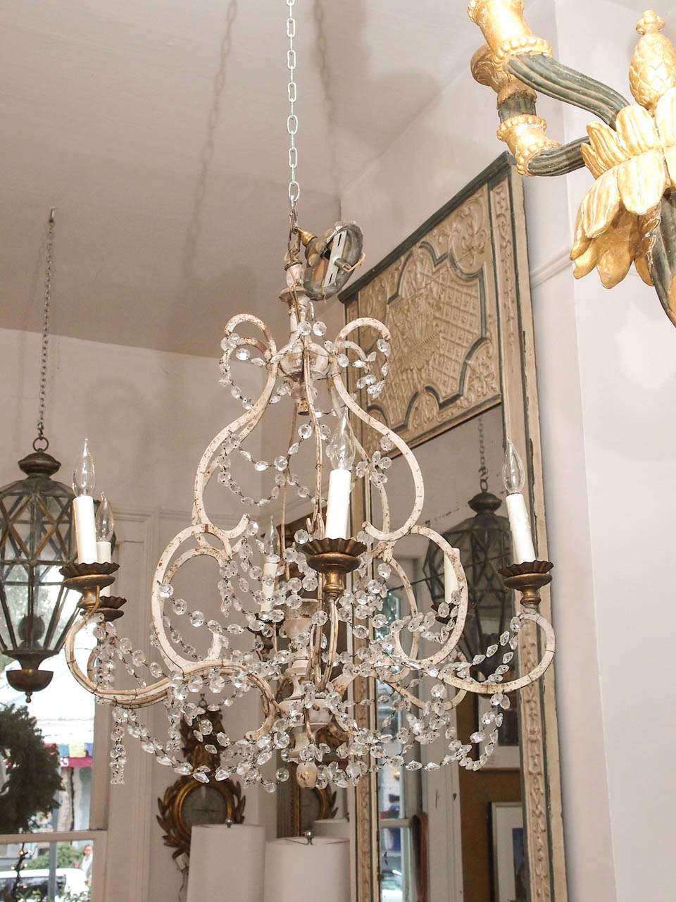 Delicate chandelier with six lights, a painted iron frame, crystal swags and a center wooden posts.