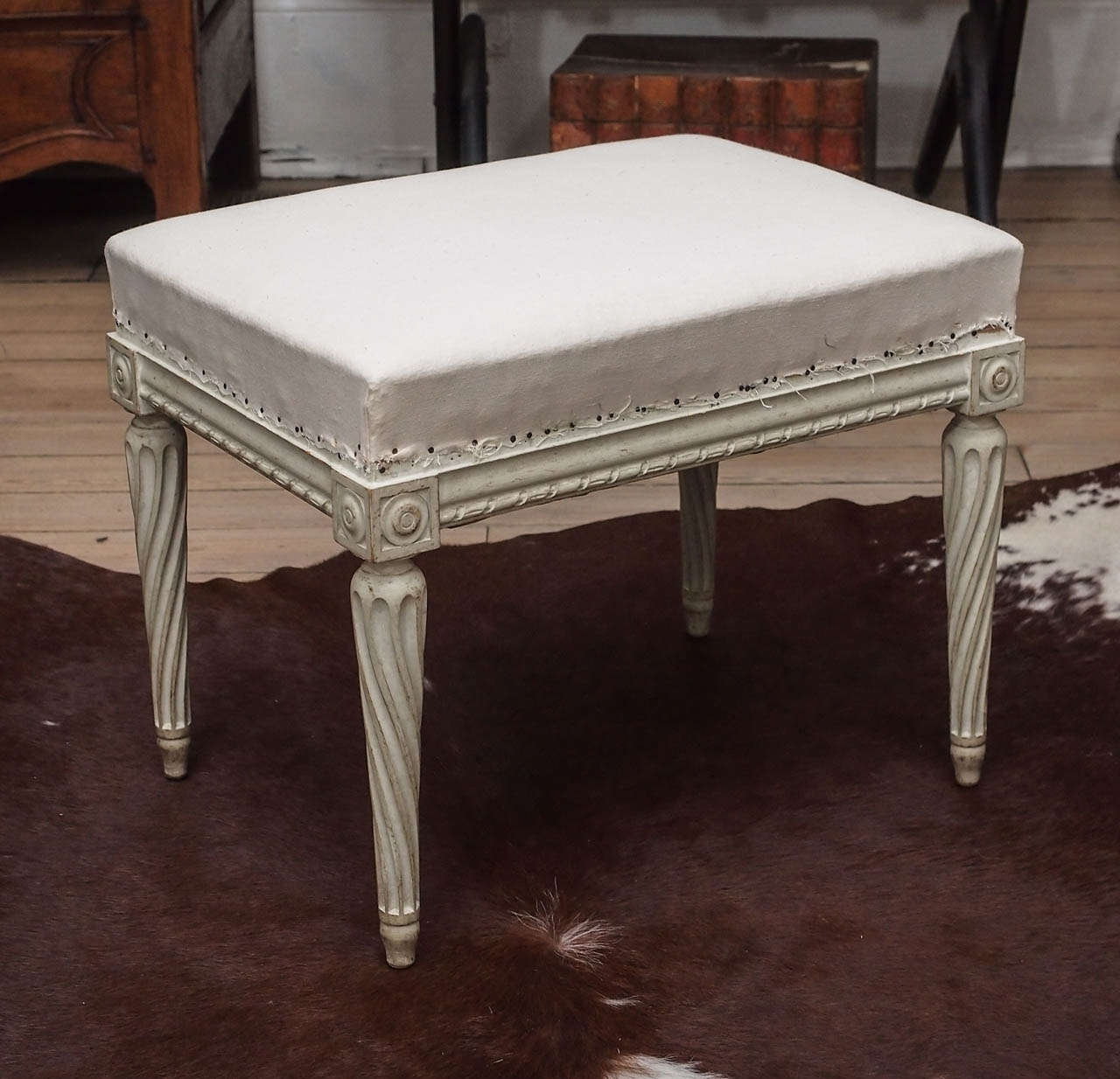 Beautiful pair of Louis XVI benches. Wood painted in antique white finish. Detailed carving around the base with fluted legs. Seat in covered in muslin, ready to be upholstered