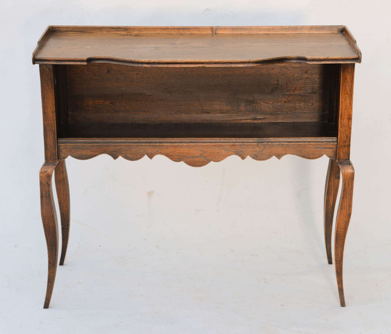 Bookcase console, of oak, having raised gallery, single shelf with trefoil cutout at each end, waved frieze and stylized cabriole legs.

Stock ID: D6671