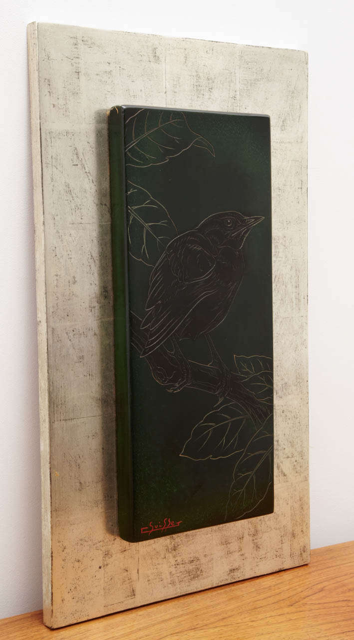 Rectangular lacquered wood panel with a blackbird on a branch, by Gaston Suisse, 1930s.
Rare dark green ground.
Signed in lower left. 
Silvered wood base. H48 X l.28 cm.

Gaston Suisse (Paris 1896-1988), specialist in lacquer after the Ecole des
