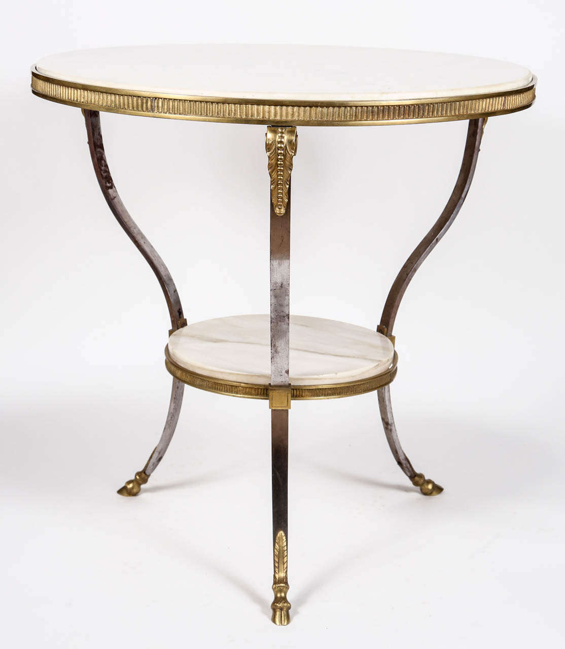 Round table with two tiers of French marble in brass and steel frame.  Stamped holt feet.  We are informed this piece was made in Italy, circa 1920s.