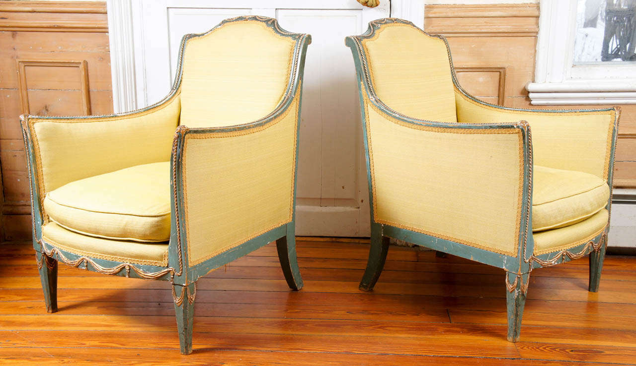 Pair of Italian neoclassical style green-painted and parcel-gilt armchairs.
Loose cushion. Lovely gilt swag and classical urn decoration on chair
crest as well as on lower rail. Yellow upholstery.