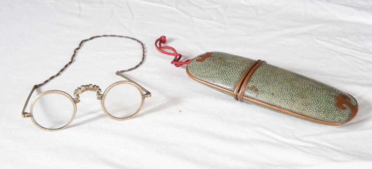 Late 19th-early 20th century Chinese green shagreen brass-mounted eyeglass case with burgundy knotted cord to hang case on belt. Steel framed glasses with crystal lenses, dragon bridge and chain. Glasses fit neatly into case. Measurement is for the