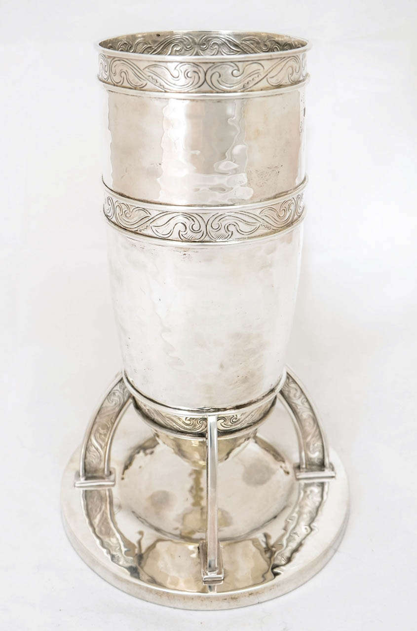 An English sterling silver vase of Arts & Crafts design, made by William Hutton & Sons in London, 1905.
The vase is 22cms high; the diameter of the opening is 9.2cms; and the base is 13.5cms. The weight is 632gms.